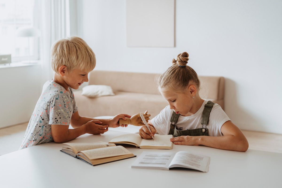 Two children reading books together on their own